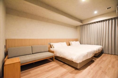 广岛Randor Hotel Hiroshima Prestige的小房间设有床和沙发