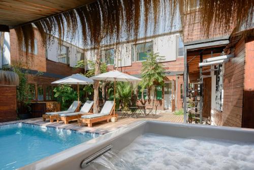 圣地亚哥Verde Madera Hostel B&B的一座带椅子和遮阳伞的游泳池位于一座建筑旁边