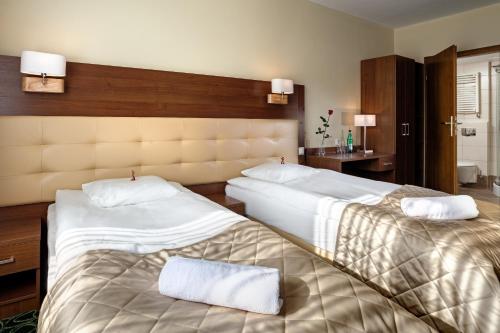 卢布林皇家植物园酒店的酒店客房,配有两张带白色床单的床