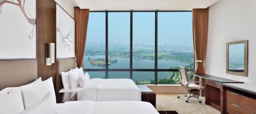 加尔各答加尔各答威斯汀酒店的酒店客房设有两张床、一张桌子和大窗户。
