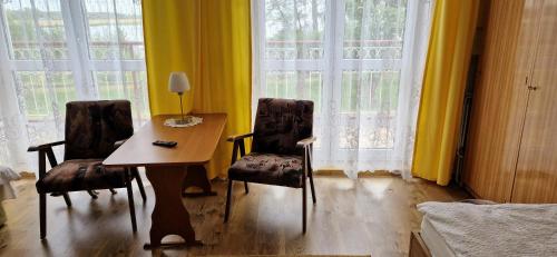 瓦济Dom Wczasowy Orka的窗户前配有一张桌子和两把椅子的房间