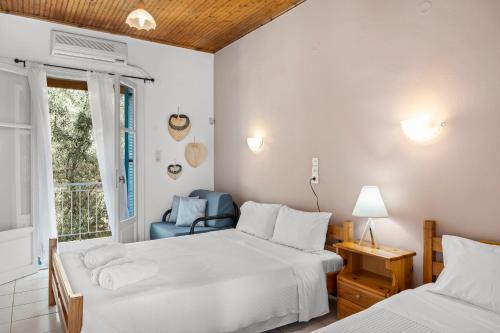 米克罗斯雅洛斯Oceanis Rooms的一间卧室设有两张床、一把椅子和一个窗户。