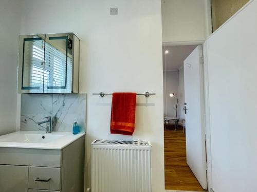 滨海绍森德NEW modernised flat in the heart of Leigh on Sea的一间带水槽和红色毛巾的浴室