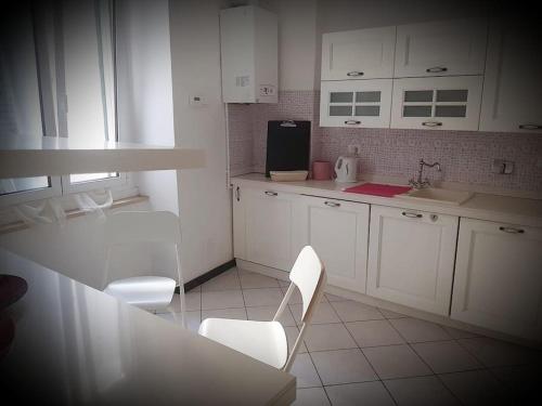 热那亚APPARTAMENTI IN GENOVA DALLO ZIO 150 mq的厨房配有白色橱柜和桌椅