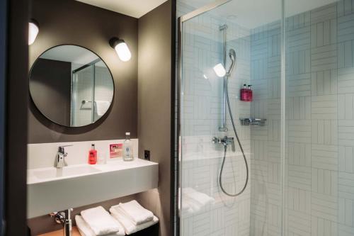 锡永Moxy Sion的带淋浴、盥洗盆和镜子的浴室
