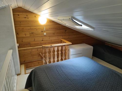 易拉斯加威Ylläs Nilimaja的一间小卧室,卧室内配有一张床铺,卧室拥有木墙