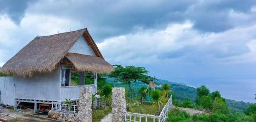 珀尼达岛Ocean Glamping Penida的山坡上带草屋顶的小房子