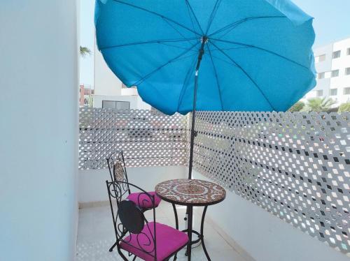 塞拉Your Airport Oasis Resort 15 Minutes from Rabat的阳台配有带蓝伞的桌椅