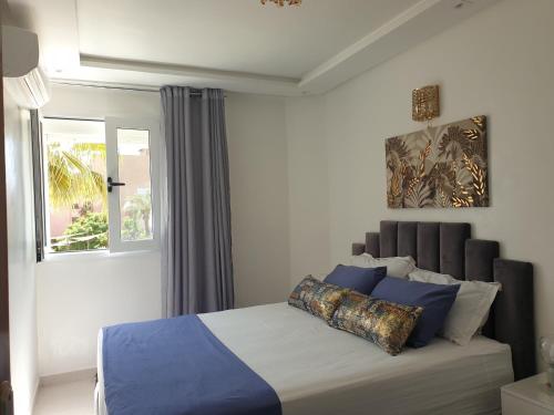 马拉喀什Bel appartement moderne au cœur de guelize的一间卧室配有一张带蓝色枕头的床和一扇窗户。