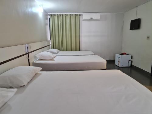 巴西利亚Hotel Montana Aeroporto的配有白色床单的客房内的两张床