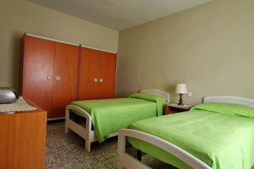 斯蒂亚Casa Lichio的配有绿床单和木柜的客房内的两张床