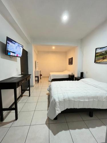塔斯科·德·阿拉尔孔ÁRBOL DE LA VIDA的一间卧室配有两张床、一张桌子和一台平面电视。