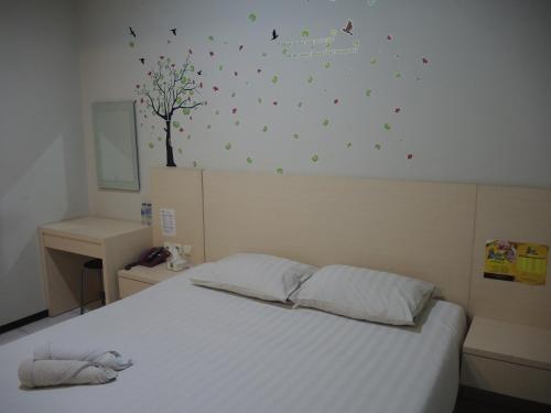 泗水SWK95号酒店的卧室配有白色的床,墙上挂着一棵树