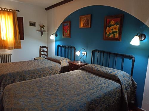 CarcabueyCortijo Entresierras的一间卧室设有两张床和蓝色的墙壁