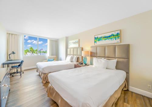 劳德代尔堡Waterview Condo- Spacious 2 bedroom - Central - Steps to Beach的酒店客房配有两张床和一张书桌
