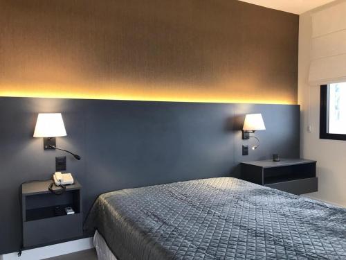 圣保罗Q-Flat Hotel - Faria Lima的卧室配有一张床,墙上配有两盏灯。