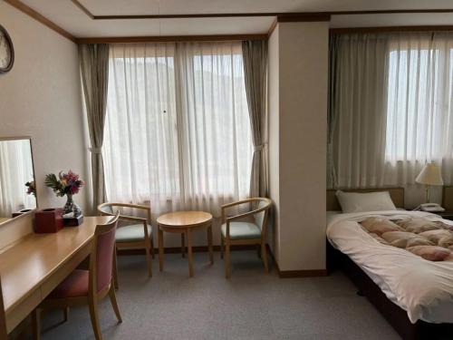 鱼沼市Asakusa Sanso的酒店客房带一张床、一张桌子和椅子