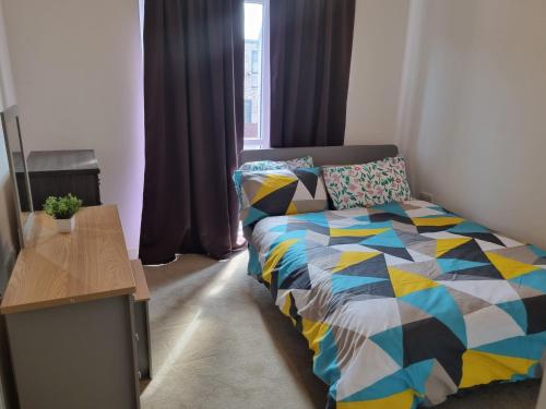 史云顿A Spacious and Hearty 2BD Swindon stay的一间卧室配有一张带五颜六色棉被的床