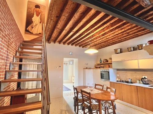 布伦塔河畔皮亚佐拉Boutique House Alle Loggie Palladiane di Villa Contarini的厨房以及带木桌和楼梯的用餐室。