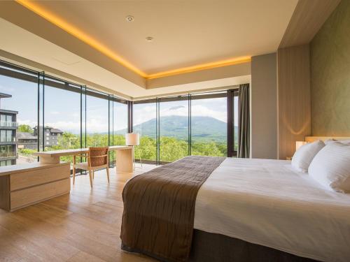 二世古新雪谷绫公寓式酒店的一间卧室配有一张大床、一张书桌和窗户。
