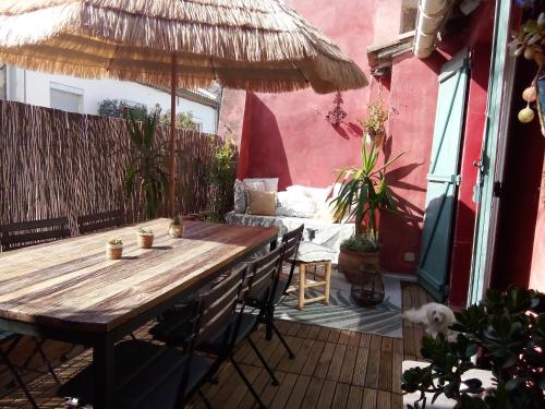 艾格-莫尔特La maison perchee的庭院里配有一张带椅子和遮阳伞的木桌