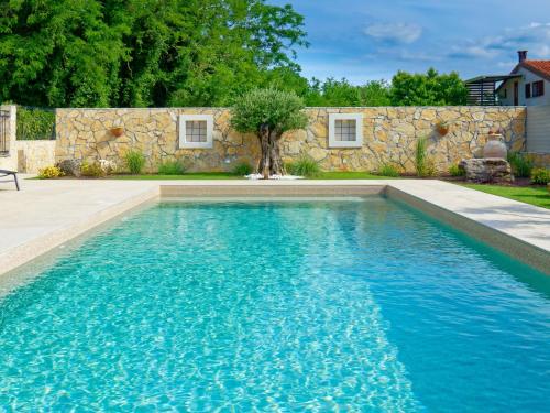 乌马格Villa Morgan的石头墙前的蓝色海水游泳池