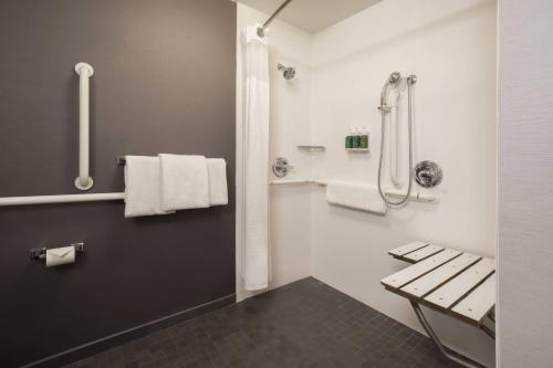 土桑图森机场万怡酒店的浴室设有长凳和带毛巾的淋浴。