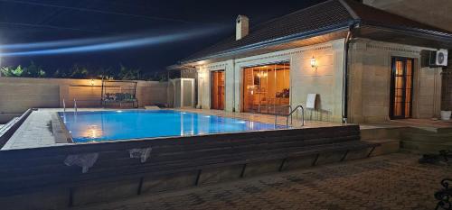 巴库Buzovna Villa的夜间在房子前面的游泳池