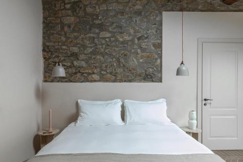 拉达-因基安蒂Pieve Aldina Relais & Châteaux的卧室配有白色的床和石墙