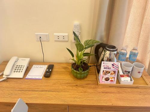 马尼拉MySpace Hotel Comembo Taguig的一张木桌,上面有电话和植物