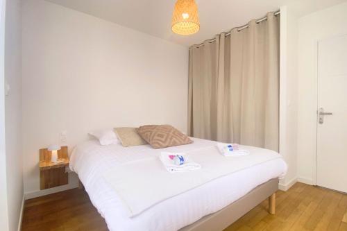 艾镇Havre de paix au cœur de la ville的卧室配有白色的床和2条毛巾