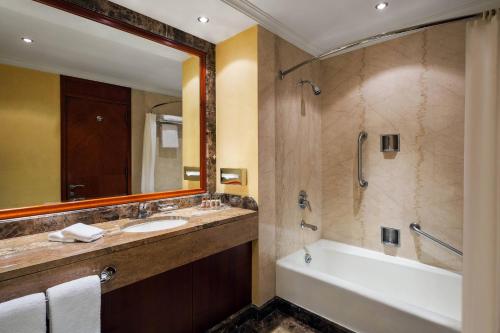 达曼达曼喜来登会议中心酒店的一间带水槽、浴缸和镜子的浴室