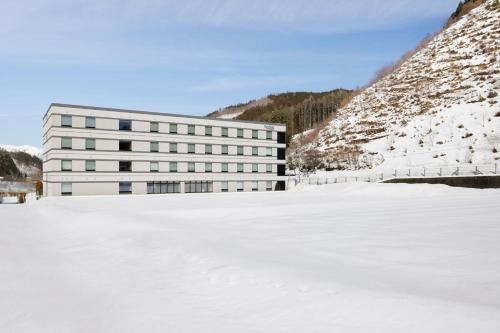 高山Fairfield by Marriott Gifu Takayama Shirakawa Go的雪地中的一座建筑,毗邻雪地