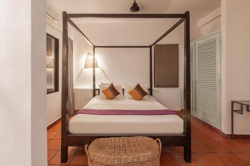 暹粒557庄园酒店的一间卧室配有一张带藤椅的天蓬床
