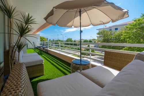 帕雷迪Belo Horizonte Apart的阳台配有沙发和遮阳伞。