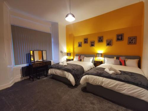 伯肯黑德Spacious 4 bed house, 7 Beds, Sofabed, Free Private Parking & Wifi的酒店客房设有两张床和电视。