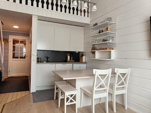 易拉斯加威Ylläs Nilimaja的厨房配有白色橱柜和桌椅