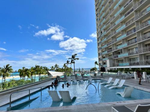 檀香山Serenity Waikiki ! Luxury Ocean Suite !的一座带白色椅子的游泳池以及一座大型建筑