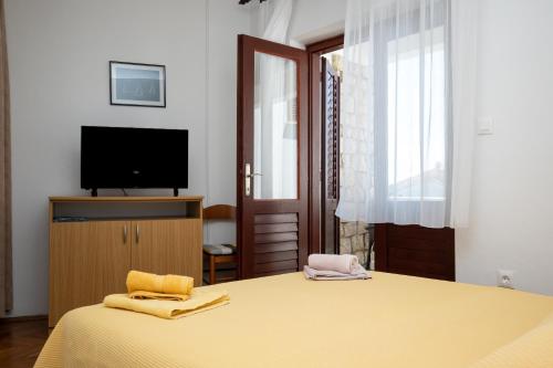 佩特坎内Apartments Morović的一间卧室配有一张带电视的床和一台陶瓷器
