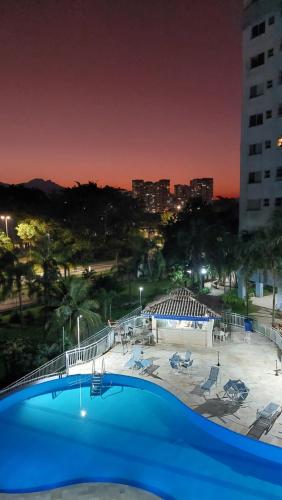 里约热内卢Apartamento Vila DR - Barra da Tijuca,prox Jeunesse,Arenas,Rio Centro,praias, Shopping的一个蓝色的大型游泳池,以城市为背景