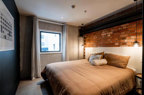 惠灵顿The Cobbler Hotel的一间卧室设有一张带砖墙的大床
