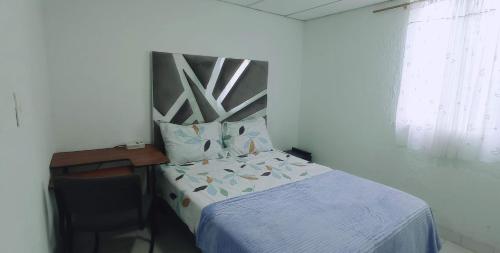 卡利CASA VASCAN的一间小卧室,配有一张床、一张书桌和一个窗户