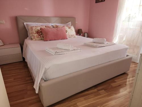 地拉那Cozy sunlit apartment with scenic balcony view的卧室配有白色大床和粉红色的墙壁