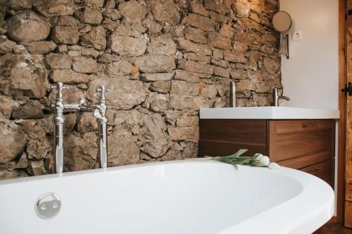 托尔明Casa di Volce - 1801 Stone House的带浴缸的浴室和石墙