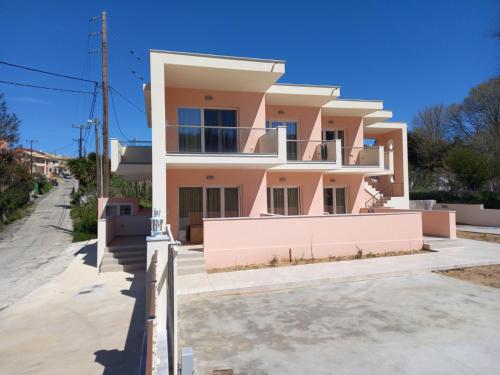 波塔莫斯AVRA-2 Apartments Potamos CORFU的粉红色的房子,前面有栅栏