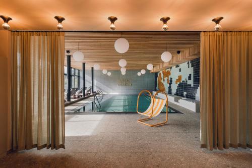巴德加斯坦The Comodo Bad Gastein, a Member of Design Hotels的一个带椅子的泳池间和一个游泳池