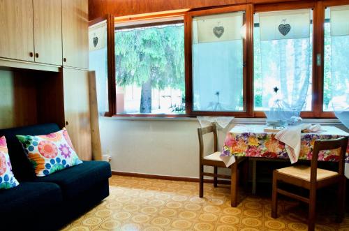 卡尔切拉尼卡阿拉戈Al Sole di TSS' - Cozy Apartment a 20 Metri dal Lago di Caldonazzo - Perfetto per coppie a Calceranica al Lago的客厅配有桌子、沙发和窗户。