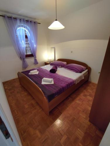 万塔西西Apartman Iva - Vantačići的一间卧室配有一张带紫色床单的床和窗户。