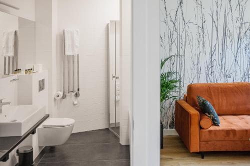华沙苹果旅馆的浴室配有橙色沙发、卫生间和盥洗盆。