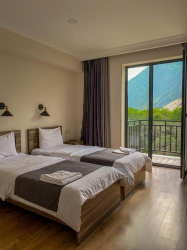 卡兹贝吉Hotel Gold Kazbegi的一间卧室设有两张床和大窗户